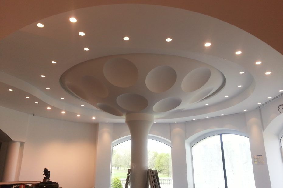 Une colonne architecturale en forme de champignon soutient un plafond en retrait présentant plusieurs niches sphériques.
