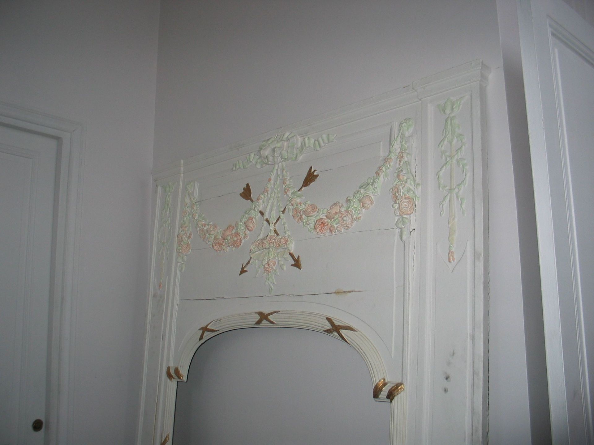 Un cadre de miroir en bois blanc orné de sculptures en relief décoratives représentant des guirlandes florales.