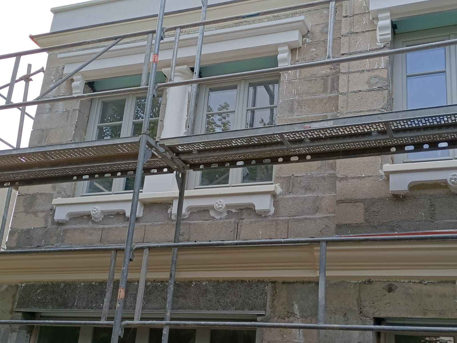 Des échafaudages masquent la façade d'un bâtiment en pierre en cours de rénovation.