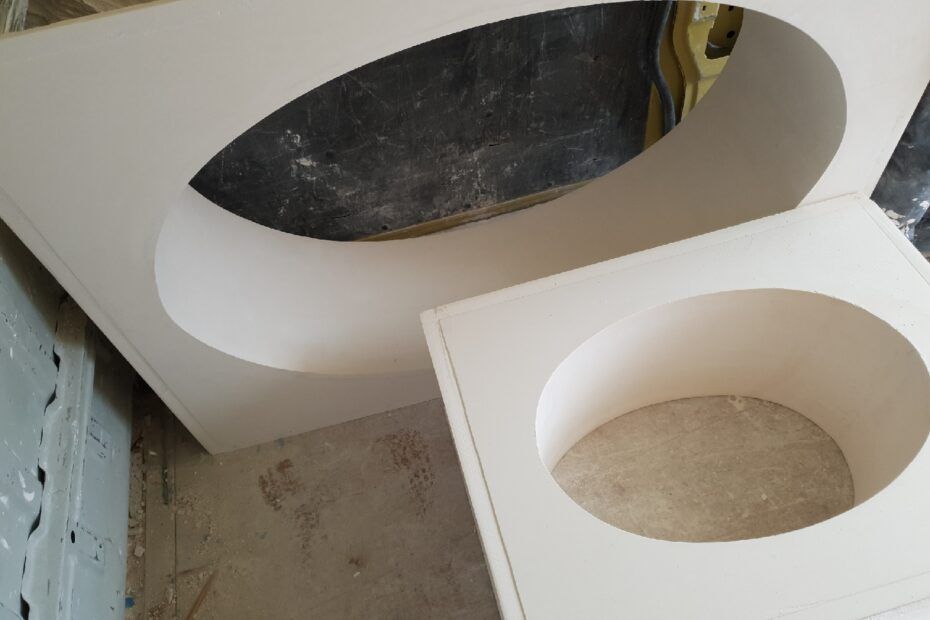 Deux panneaux de bois clair, ornés de découpes ovales assorties, reposent sur le sol d'un atelier.