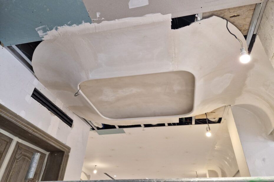 Un plafond en construction présente un détail architectural rectangulaire arrondi et encastré.