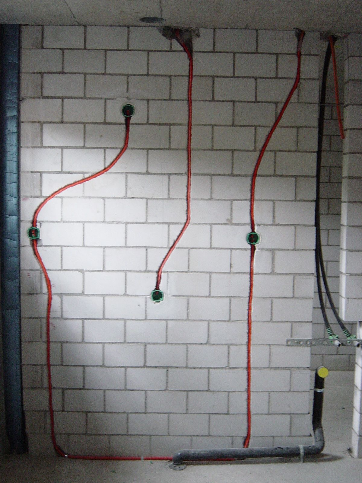 Ein im Bau befindliches Badezimmer mit Rohren und Kabeln, die von den Wänden hängen