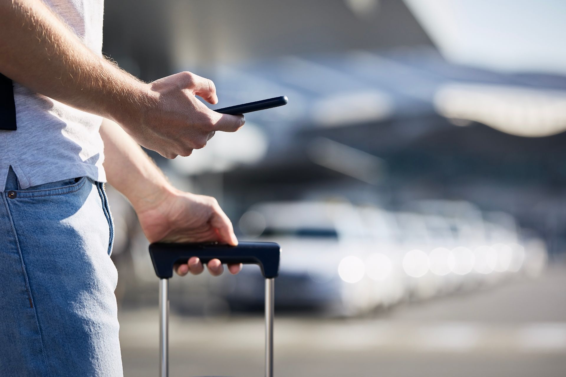 Une personne sur son téléphone, tenant sa valise.