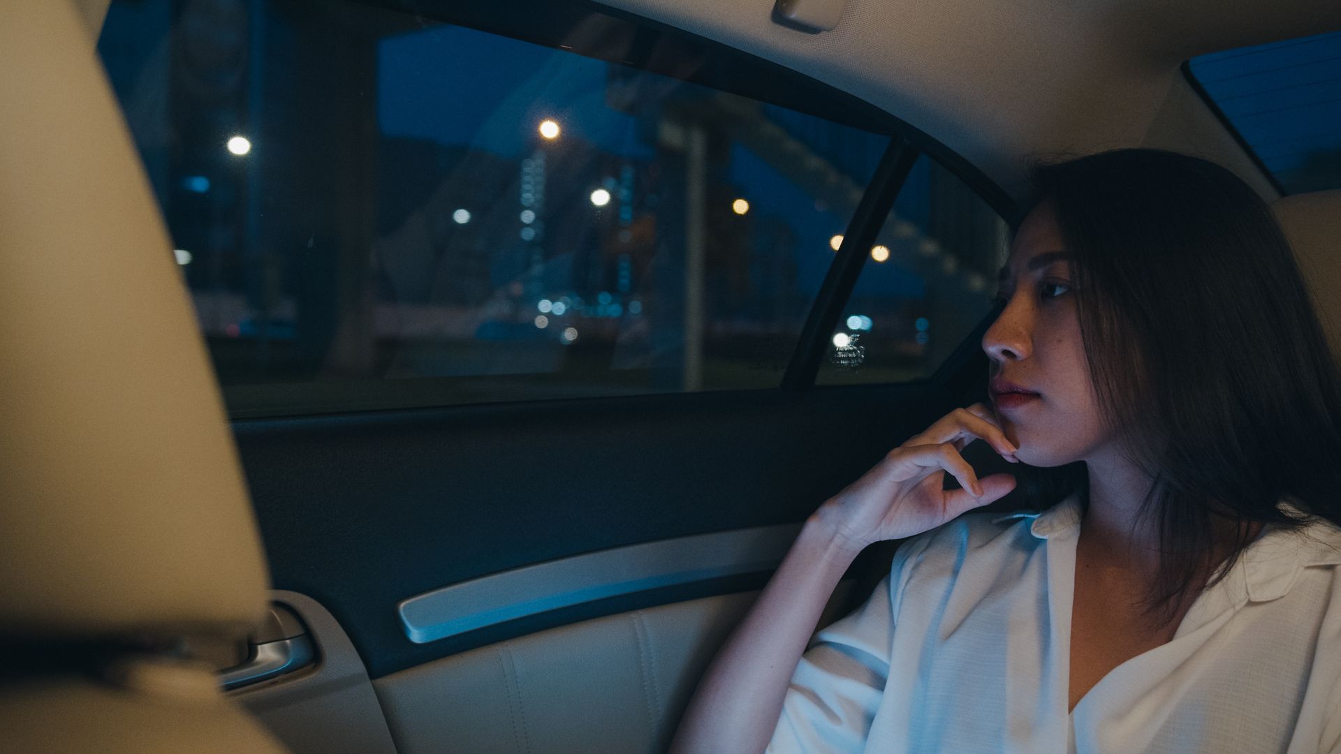 Une femme assise sur le siège arrière d'une voiture.