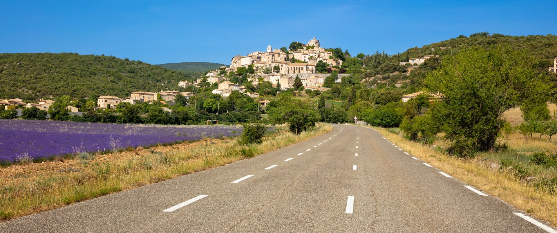 Une route avec un village en hauteur sur le côté.