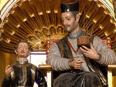 Una estatua de un hombre sentado en un trono sosteniendo una canasta.