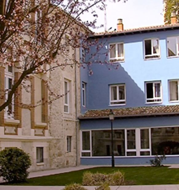 Un edificio azul con muchas ventanas se encuentra al lado de un edificio blanco.
