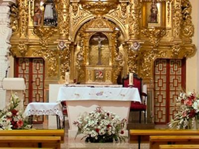 El altar de una iglesia está decorado con flores y velas.