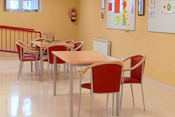 Una habitación con mesas y sillas y un extintor en la pared.