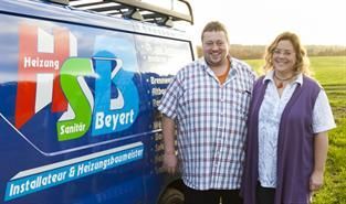 Ein Mann und eine Frau stehen vor einem blauen Lieferwagen.