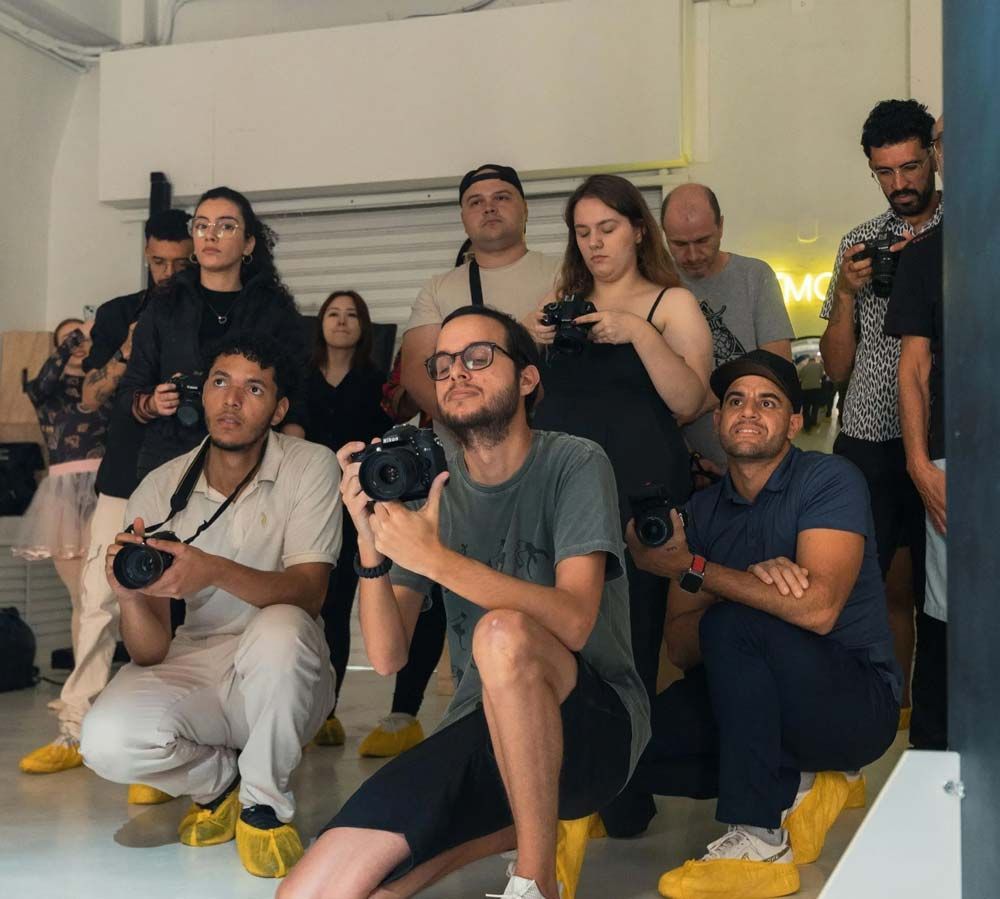 Grupo de personas posando en unas escaleras, muchas de ellas con cámaras en mano, en un luminoso interior.