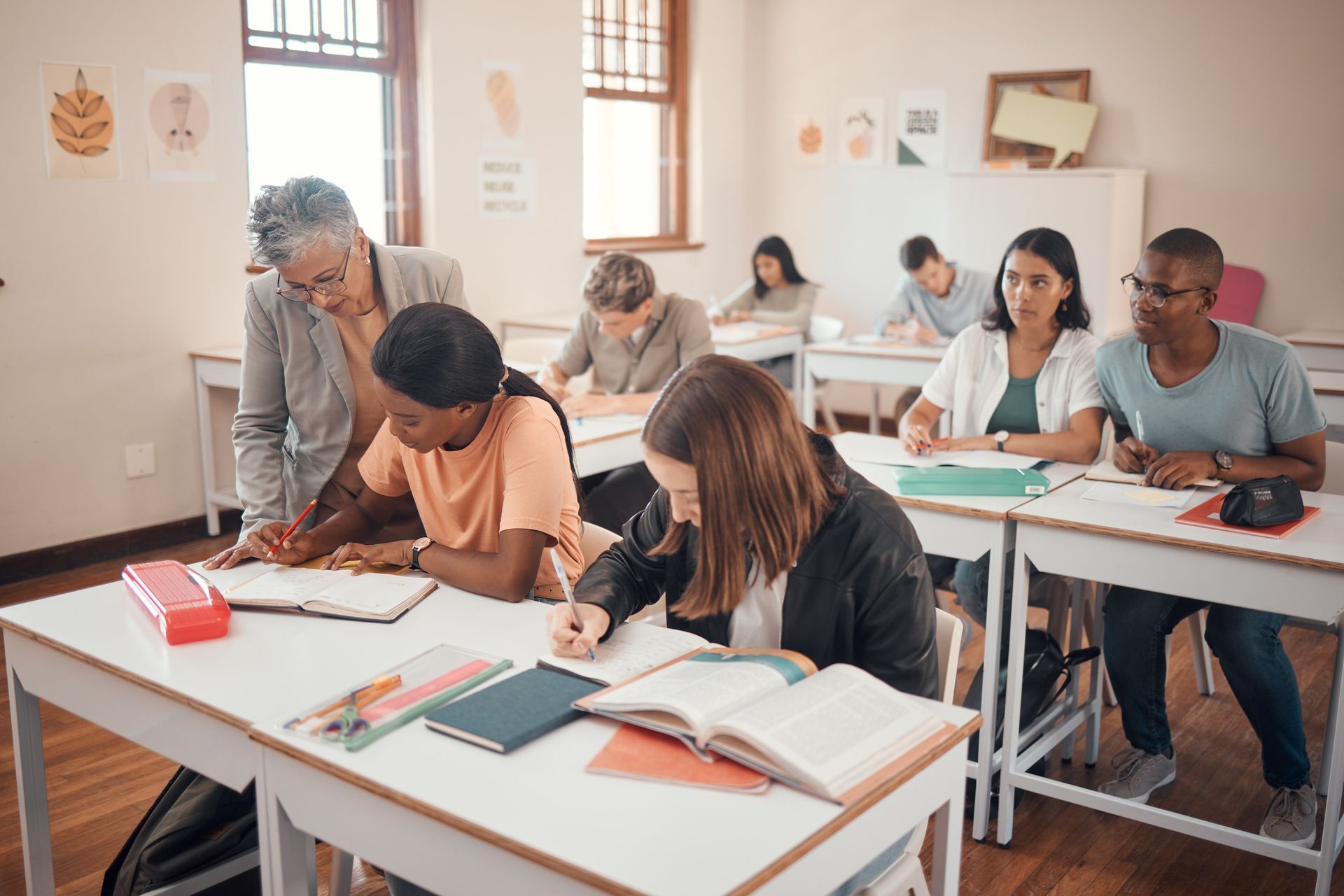 Un profesor está ayudando a un grupo de estudiantes en un aula.