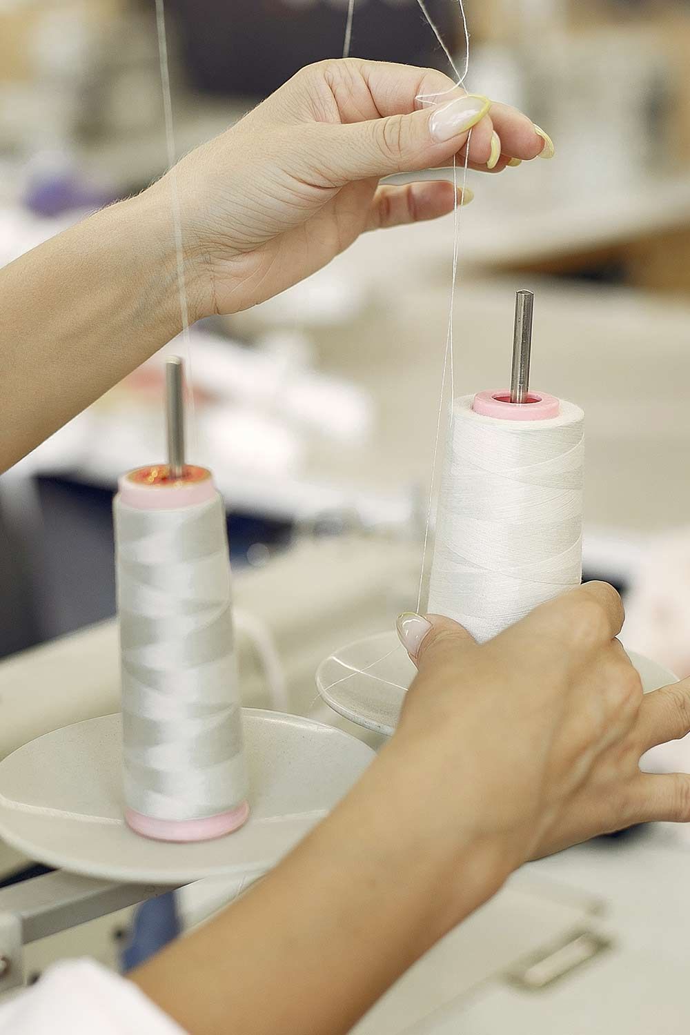 Manos encendiendo velas blancas con la parte superior rosa sobre platos en un taller.