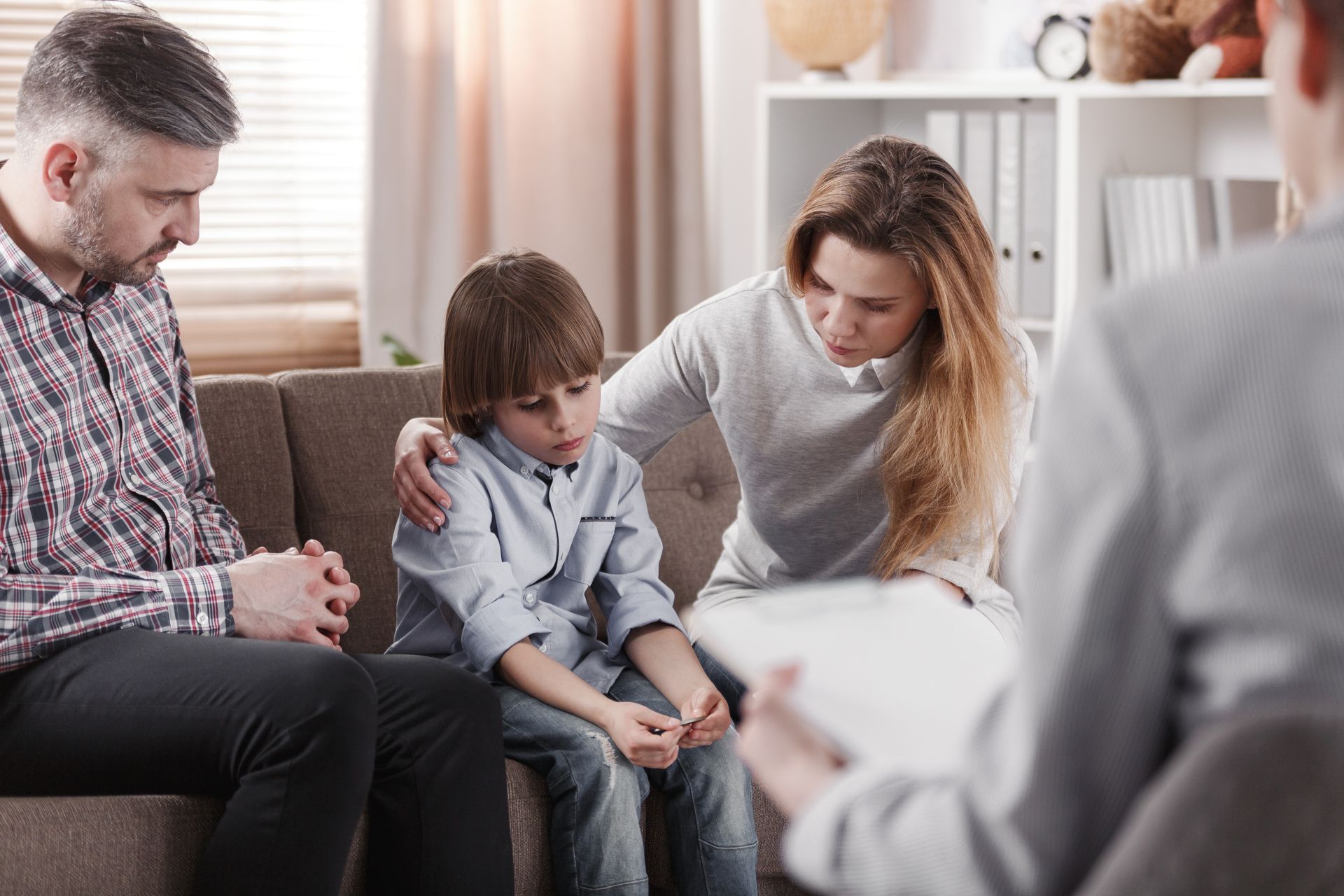 Enfant sur un canapé entouré de ses parents en instance de divorce