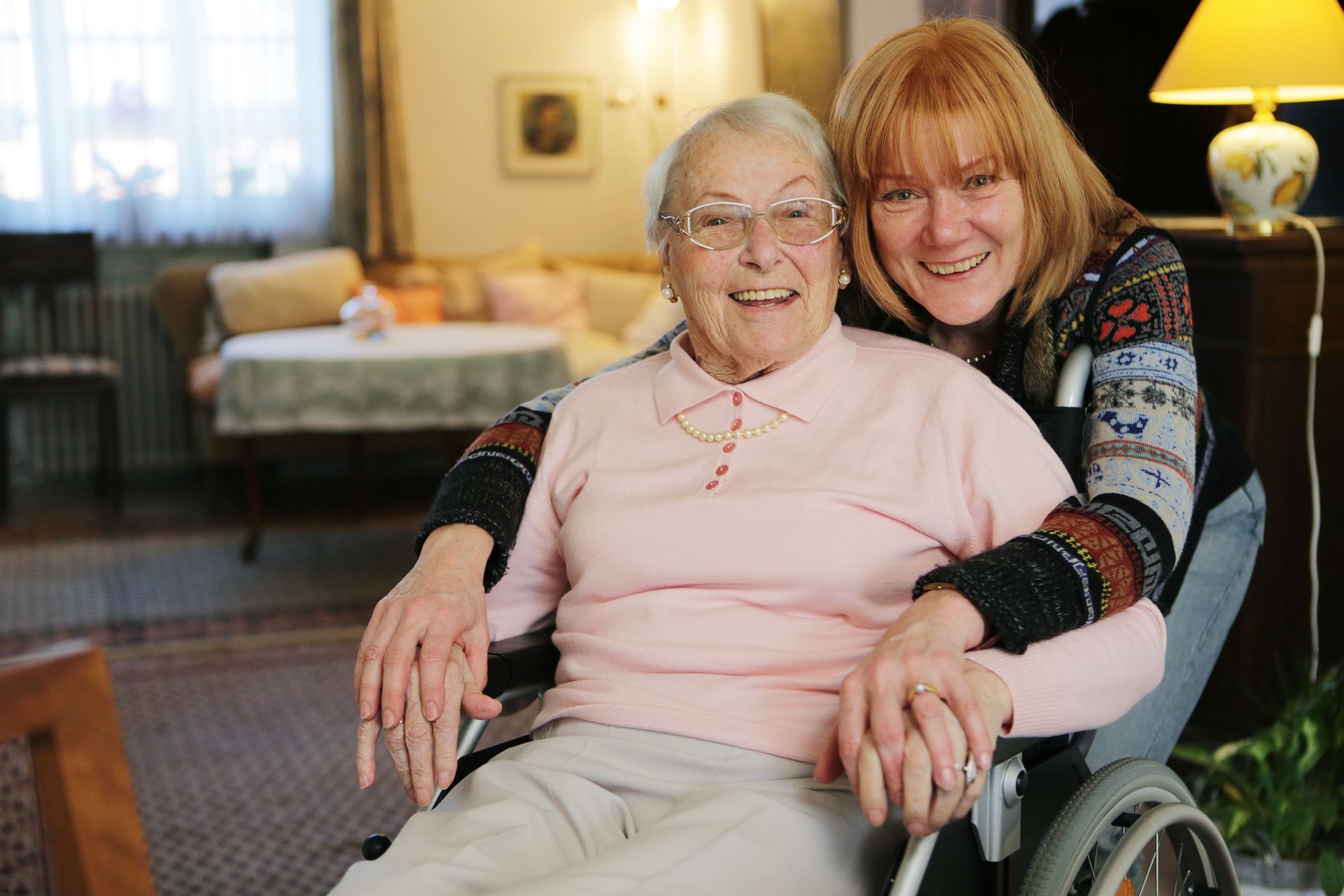 Femme agée souriante dans un fauteuil roulant avec une aide à domicile