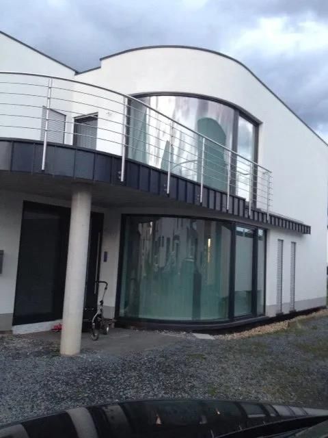 Ein weißes Haus mit einem Balkon und einem großen Fenster