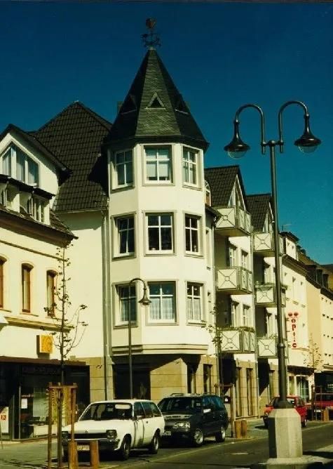 Autos sind vor einem Gebäude mit einer Wetterfahne auf dem Dach geparkt