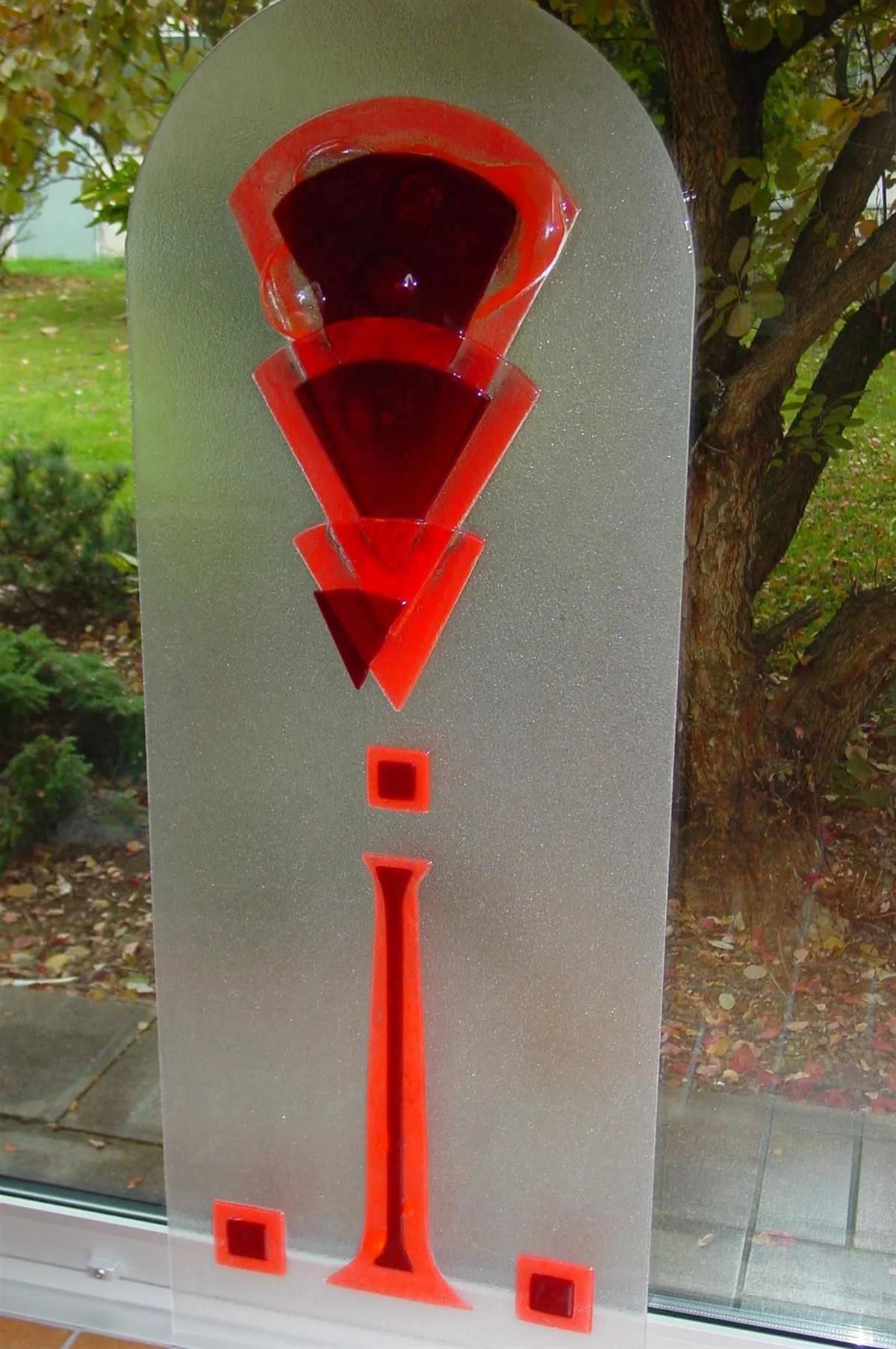 Eine Glasskulptur mit roten Dreiecken und Quadraten darauf