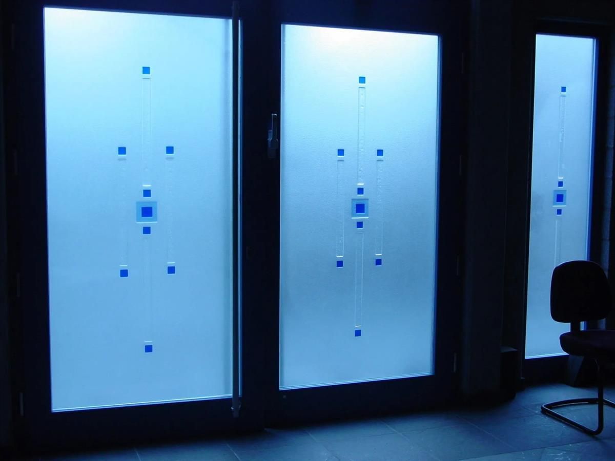 Ein Stuhl steht vor einem Fenster mit einem blauen Muster darauf