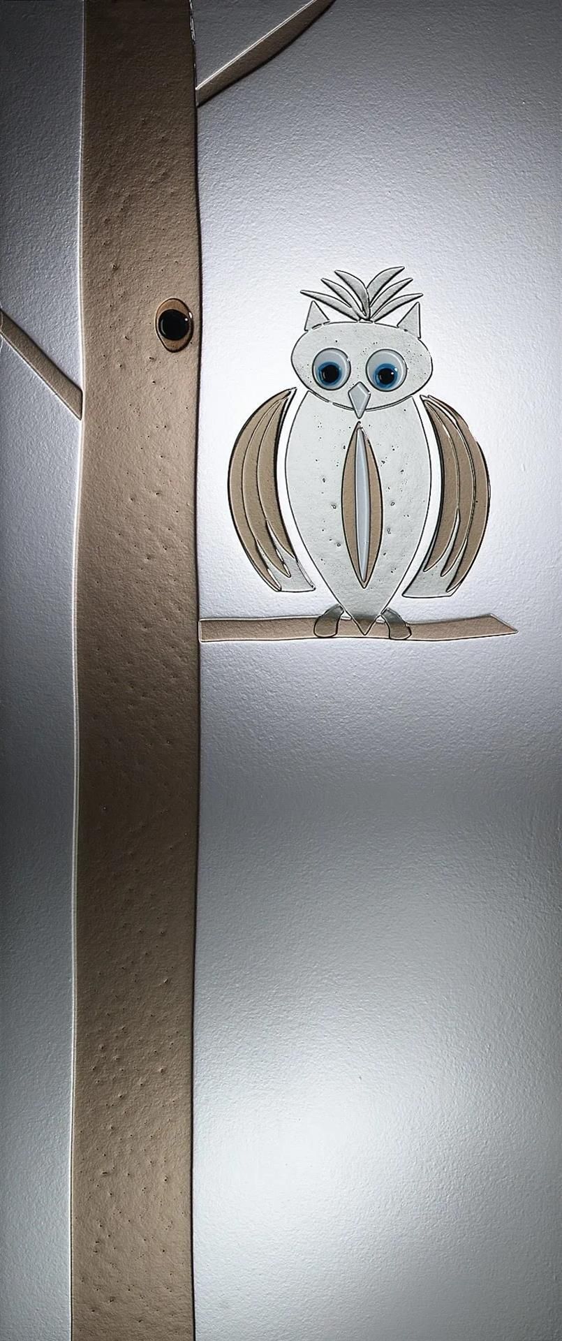 Eine Eule sitzt auf einem Ast. Im Hintergrund ist ein Vogelhäuschen zu sehen.