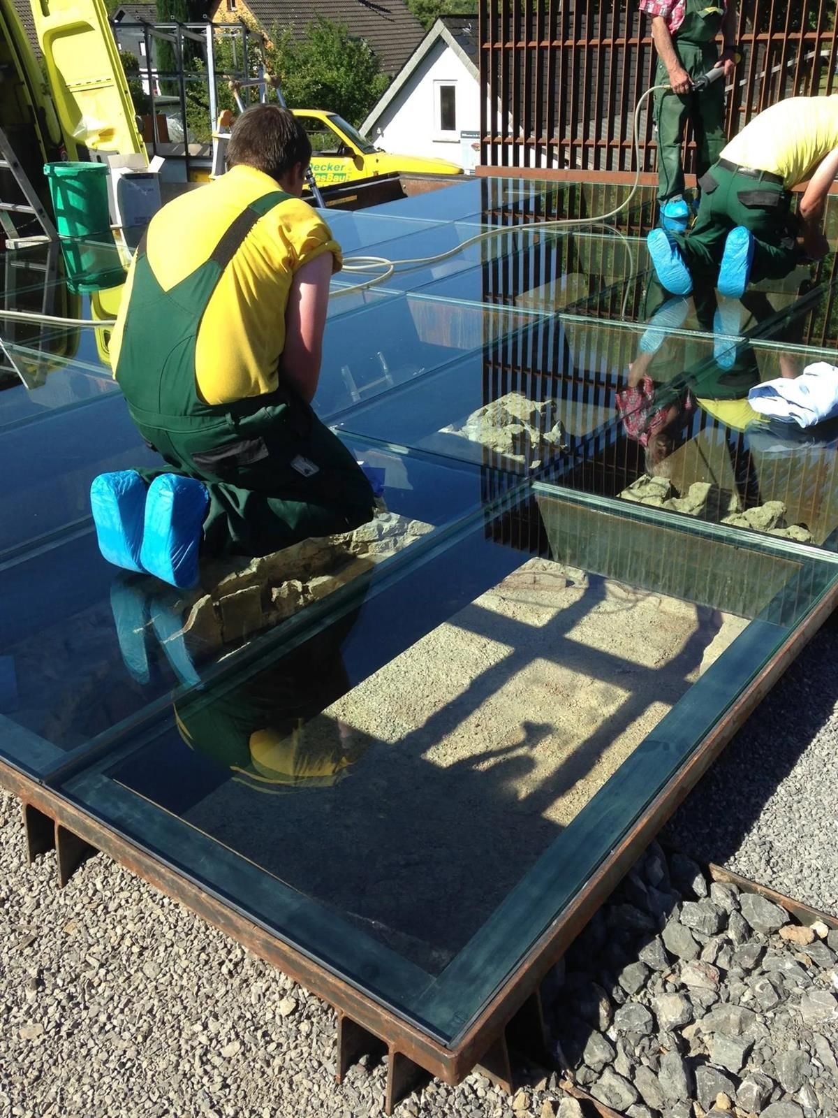 Ein Mann im Overall kniet auf einem Glasboden