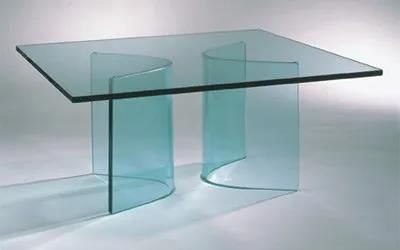Auf einer weißen Fläche steht ein Glastisch mit geschwungenen Beinen.