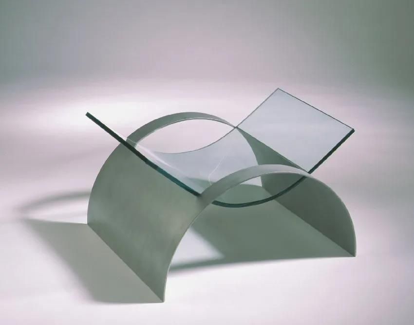 Ein Stuhl aus Glas und Metall steht auf einer weißen Fläche