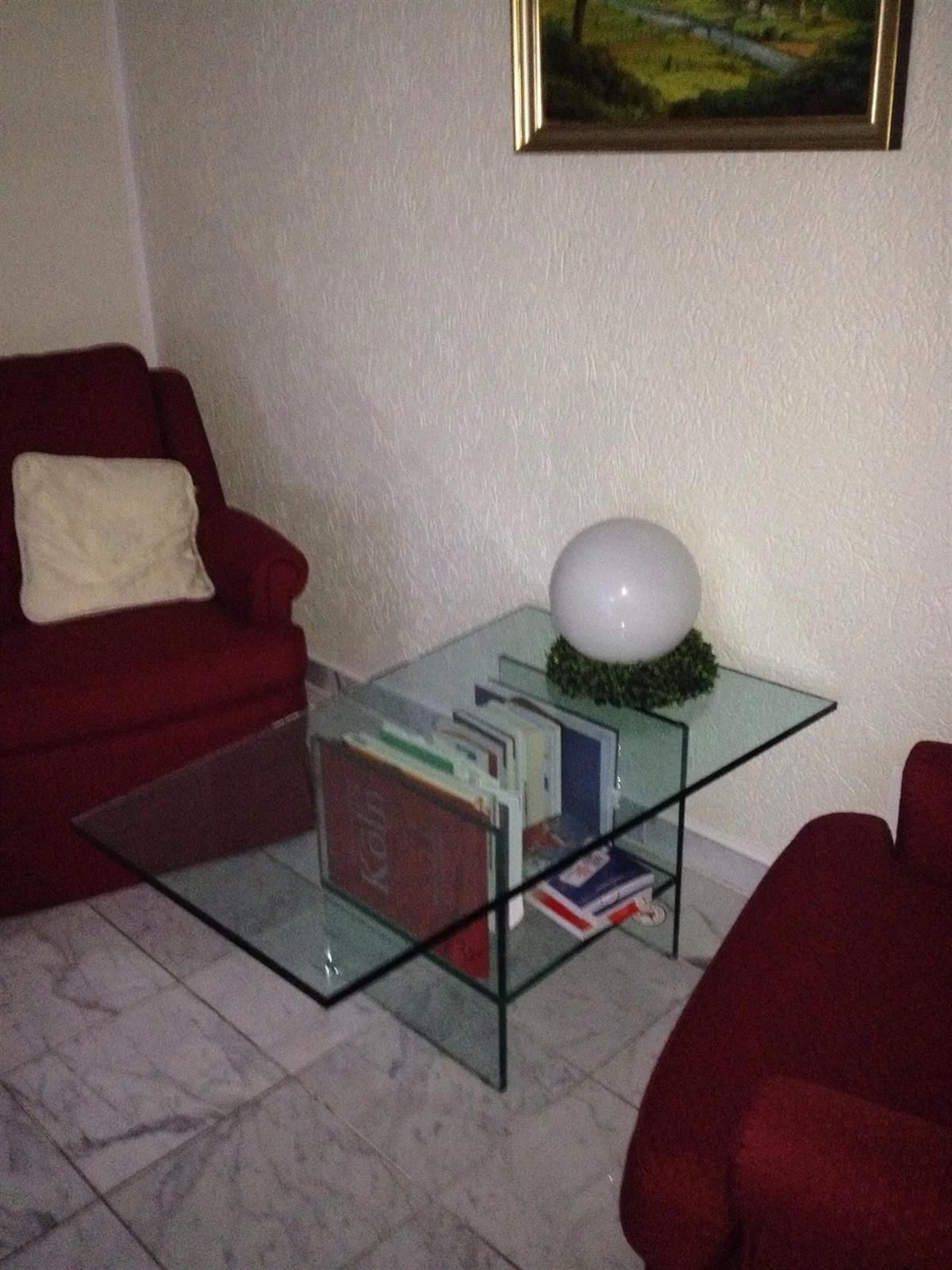 Ein Couchtisch aus Glas mit Büchern darauf in einem Wohnzimmer