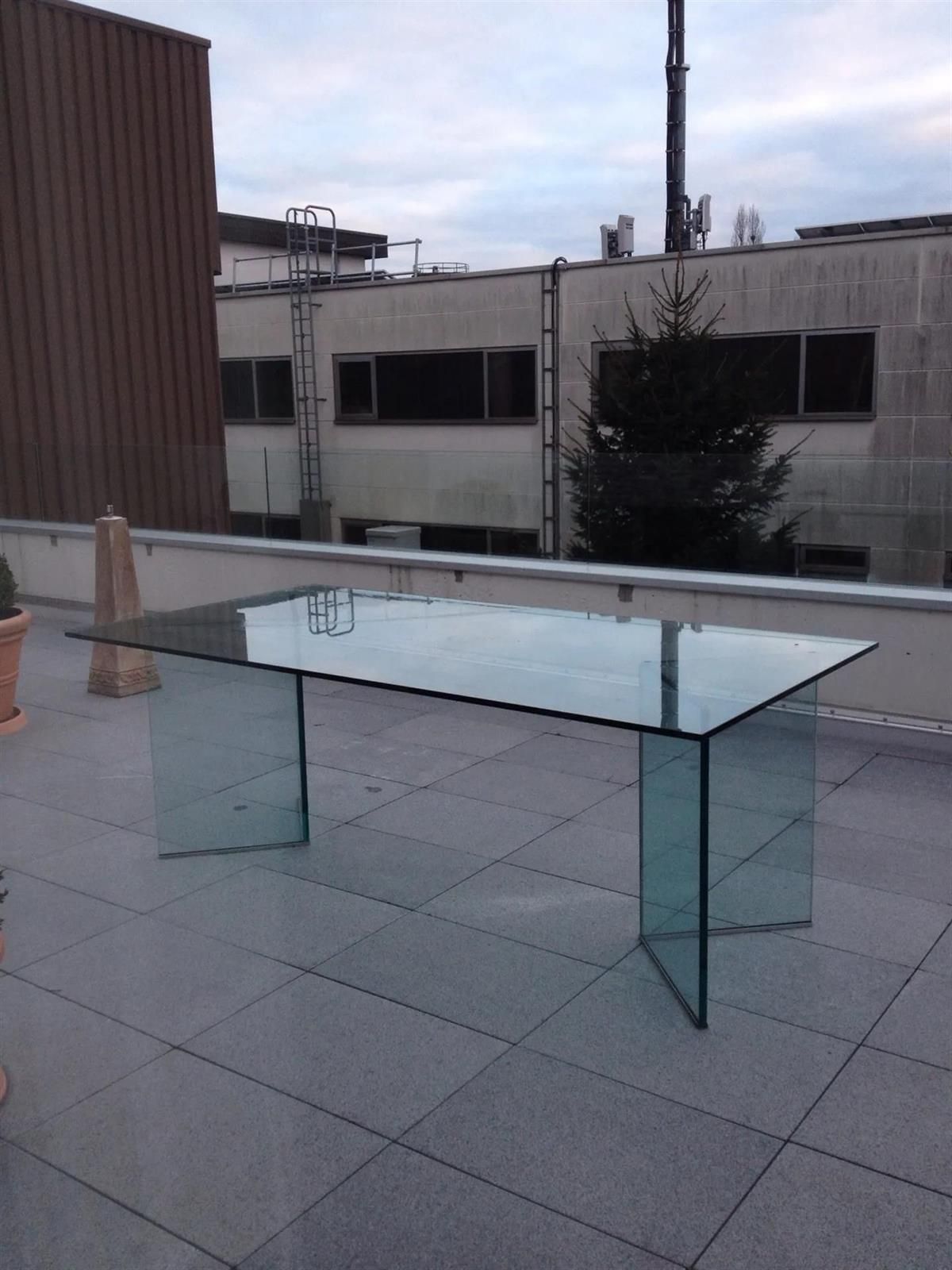 Ein Glastisch auf einem Dach mit Gebäuden im Hintergrund