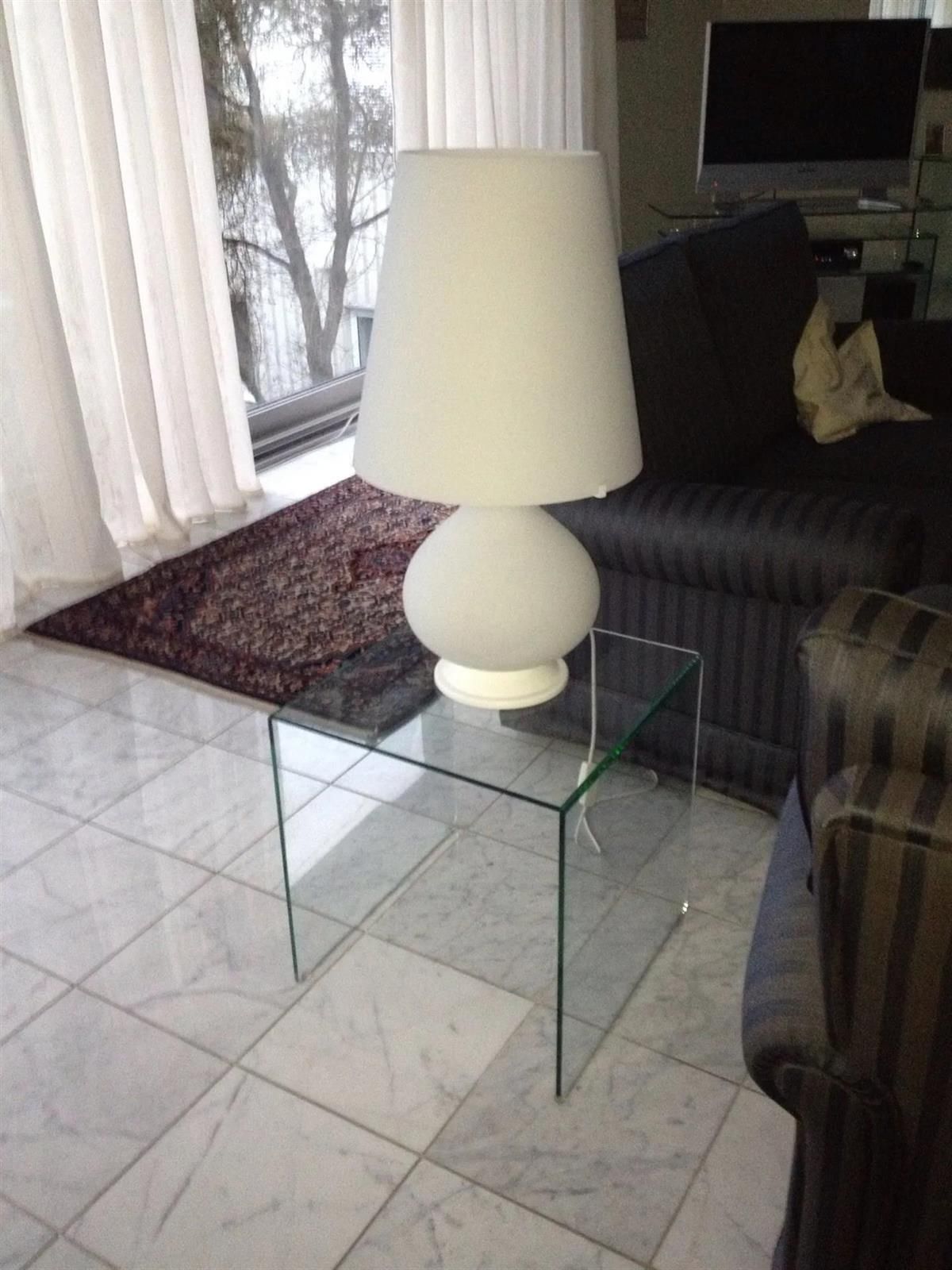 Eine Lampe steht auf einem Glastisch in einem Wohnzimmer