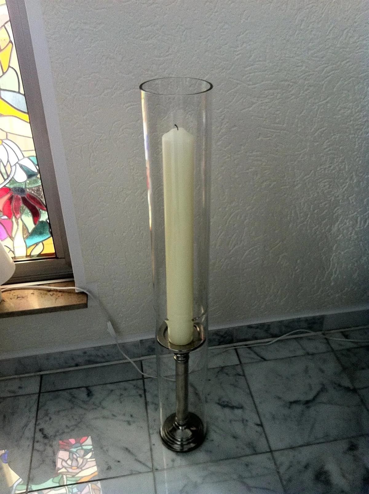 Eine hohe Glasvase mit einer Kerze darin