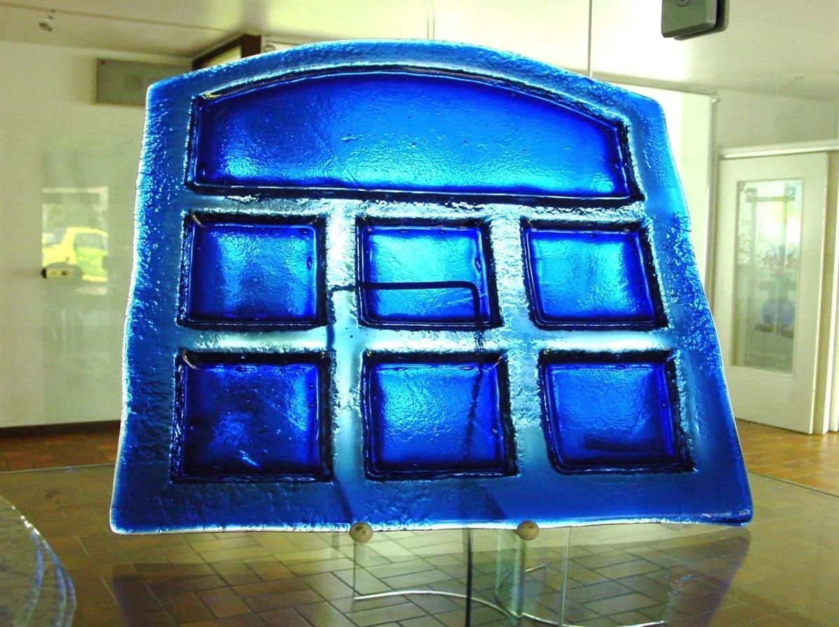 Ein blaues Buntglasfenster steht auf einem Glastisch