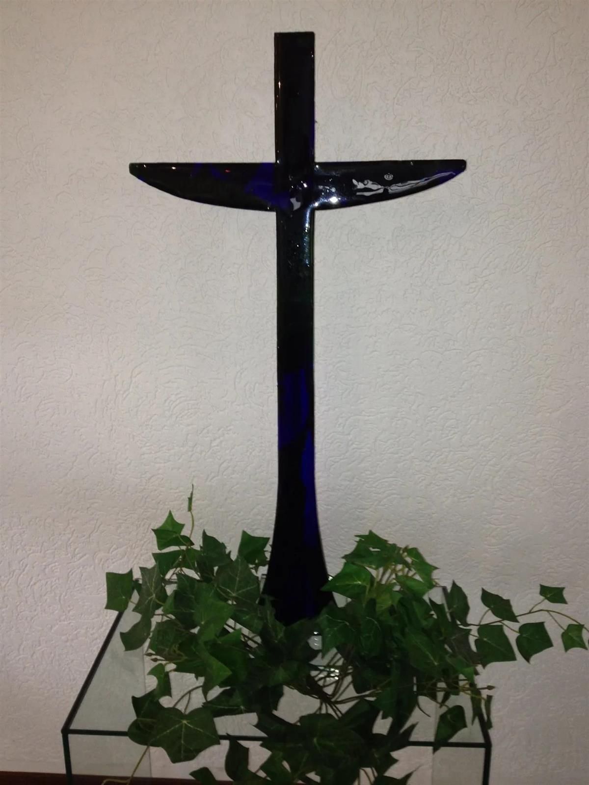 Ein blaues Glaskreuz sitzt auf einem Glasssockel