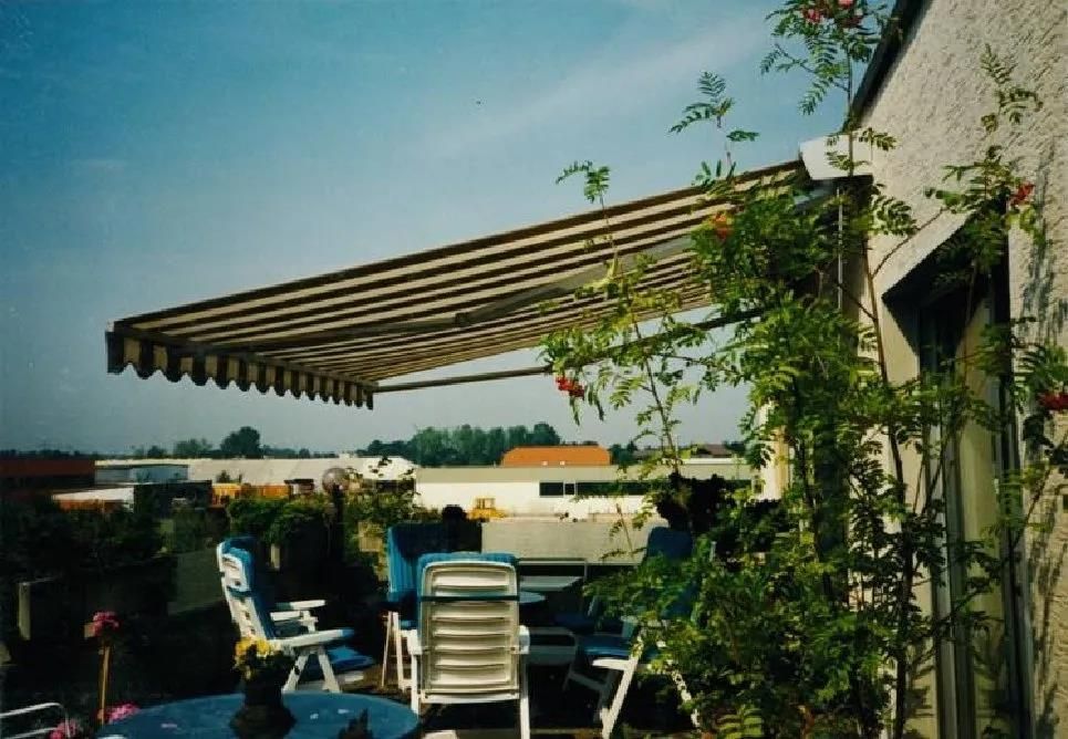 Eine Terrasse mit Tisch und Stühlen unter einer Markise