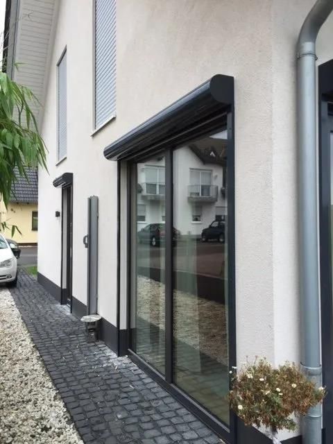 Ein weißes Haus mit einer Glasschiebetür und einem davor geparkten Auto.