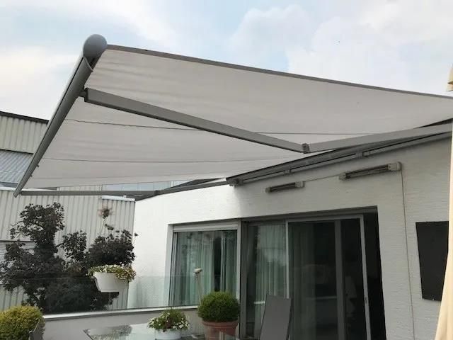 Eine weiße Markise überdacht einen Balkon mit Tisch und Stühlen.