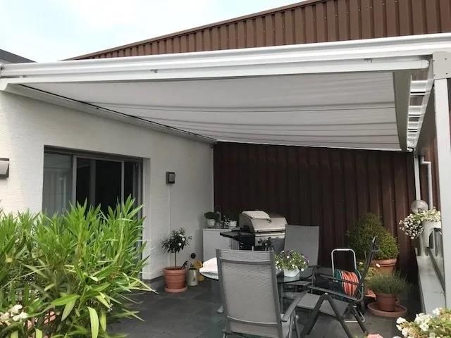 Eine Terrasse mit Tisch und Stühlen unter einem Baldachin.