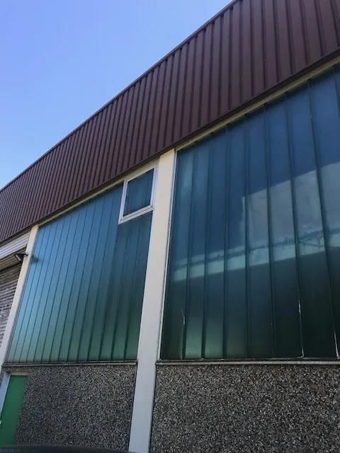Ein großes Gebäude mit grünen Fenstern und einem braunen Dach.