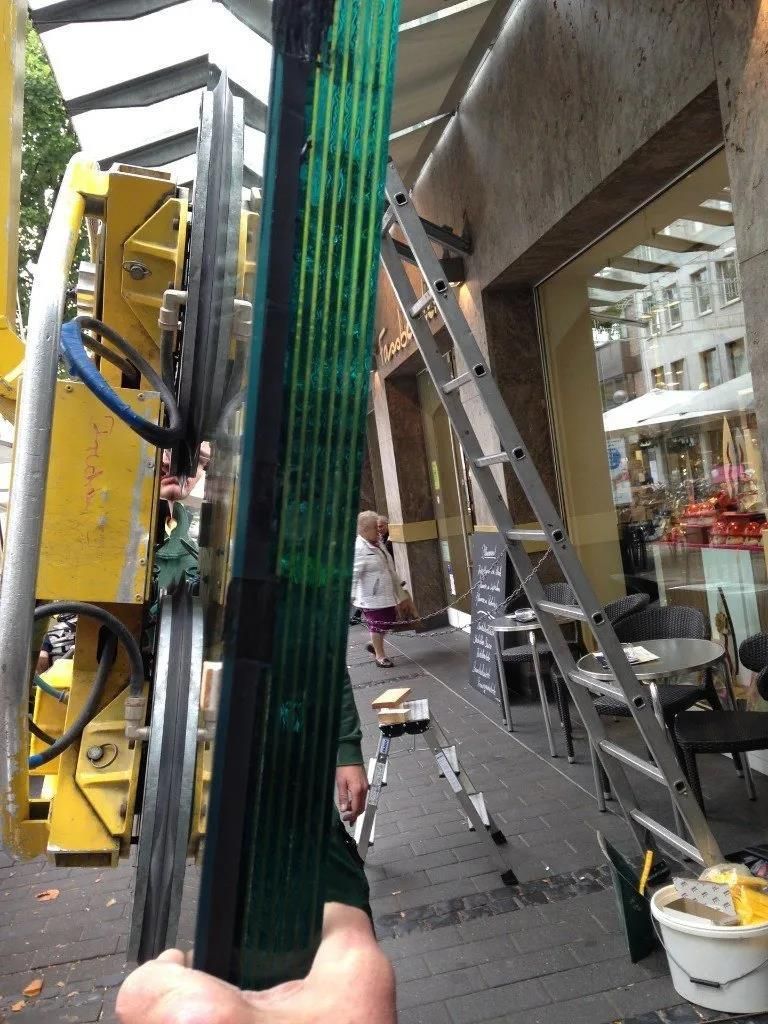 Eine Person hält ein Stück Glas vor einem Gebäude