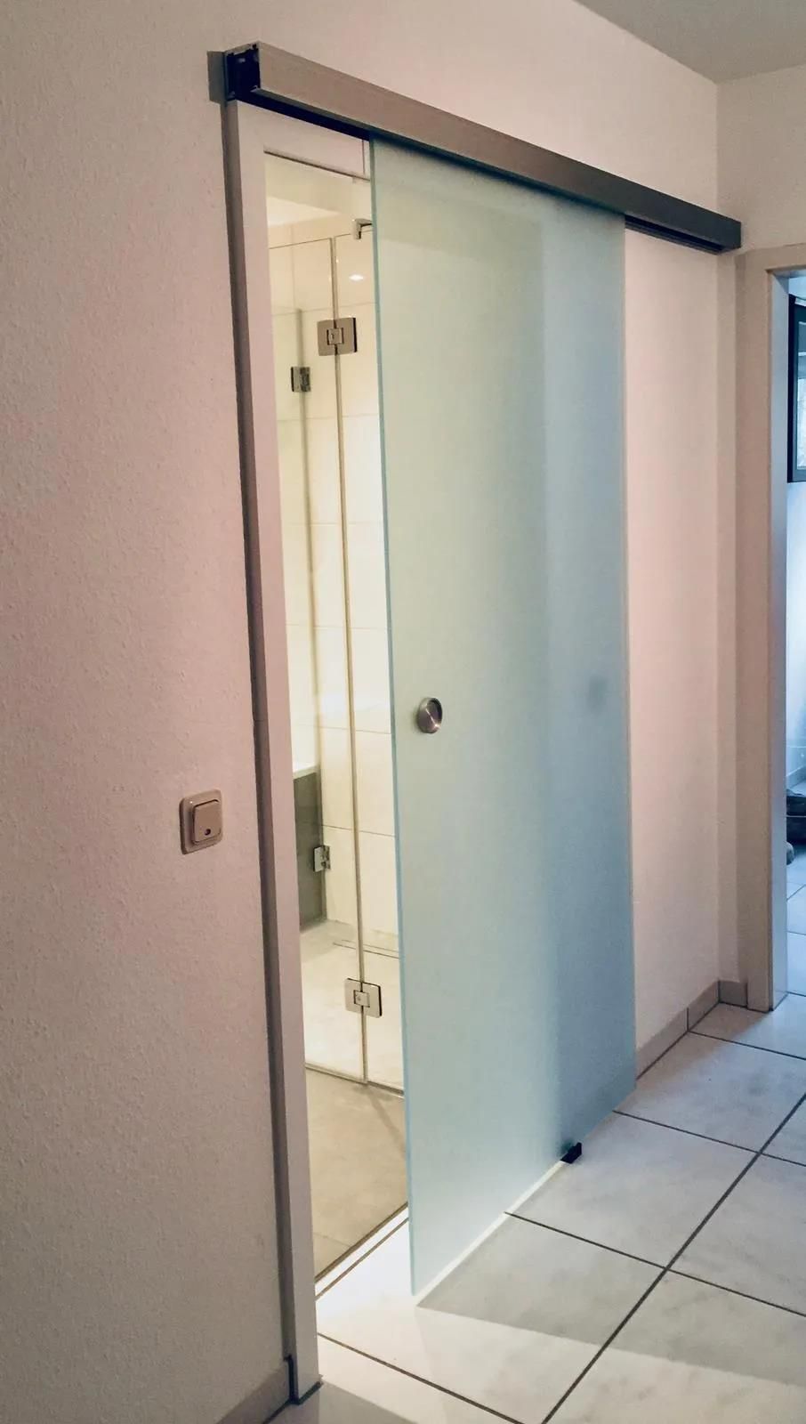 Eine Glasschiebetür führt zum Badezimmer