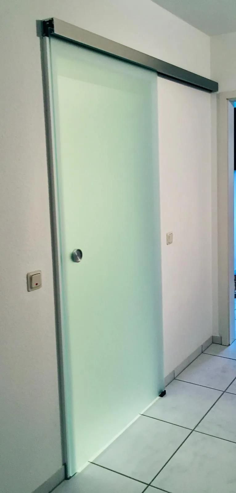 Eine Glasschiebetür in einem Flur mit weißem Fliesenboden