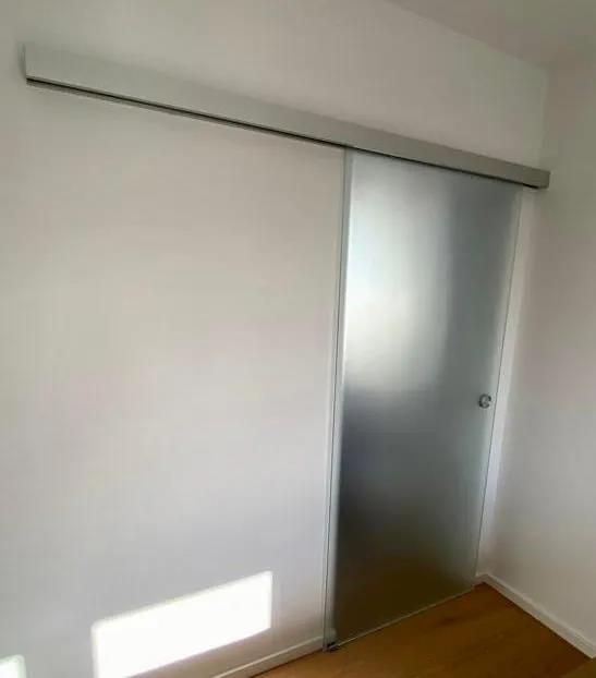 An einer weißen Wand in einem Raum hängt eine Glasschiebetür.