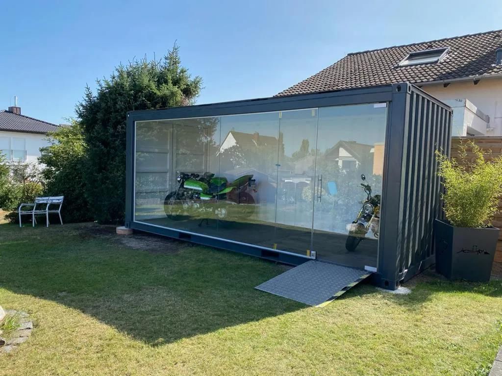 In einem Glasgebäude in einem Hinterhof ist ein Motorrad geparkt.