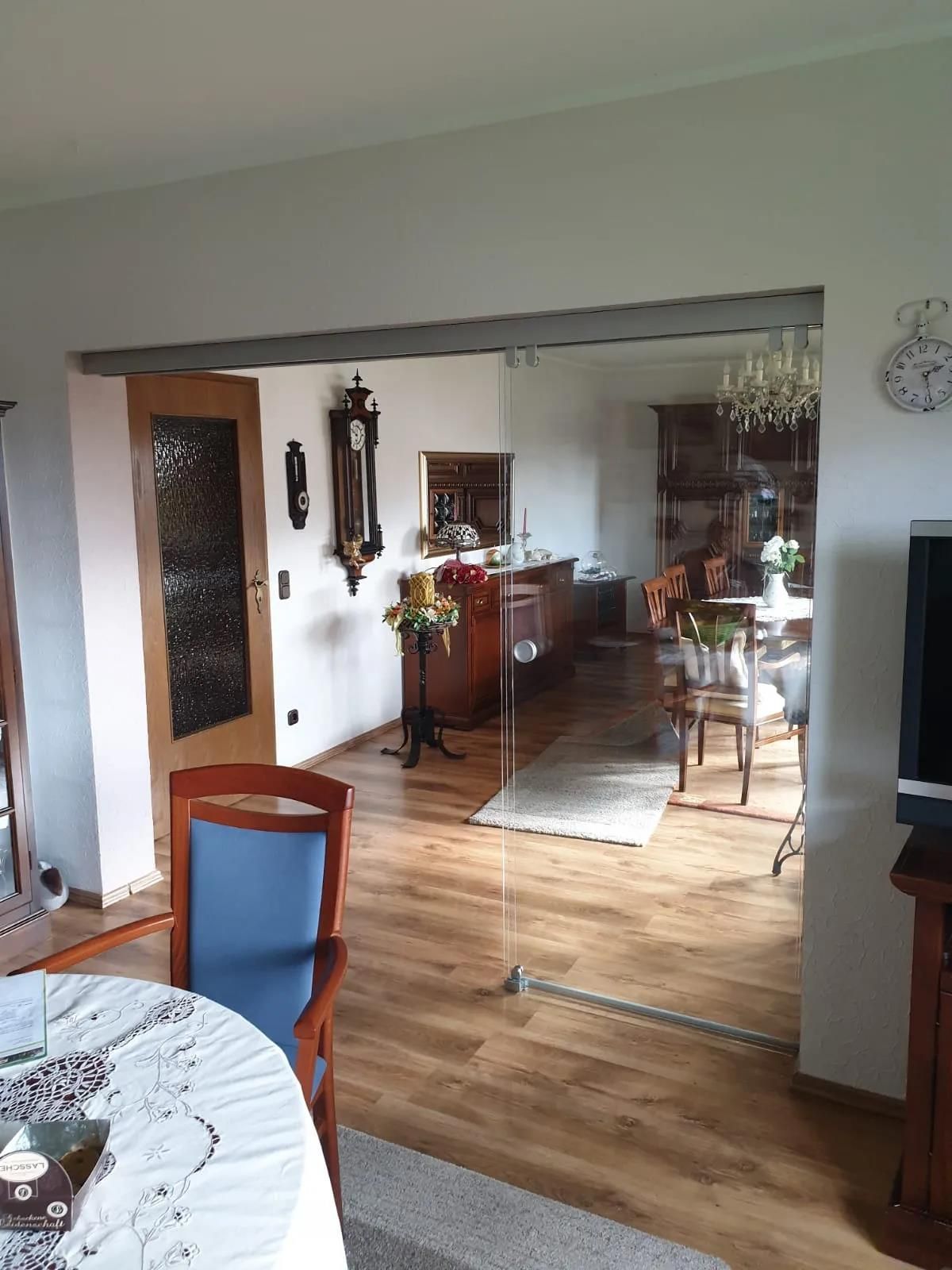 Ein Wohnzimmer mit einem Tisch und Stühlen und einer Uhr an der Wand