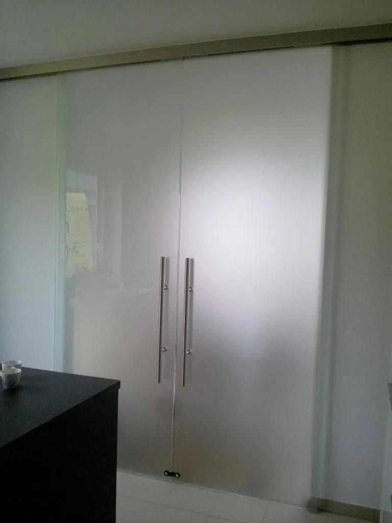 Ein Paar Glasschiebetüren mit Edelstahlgriffen in einem Raum.