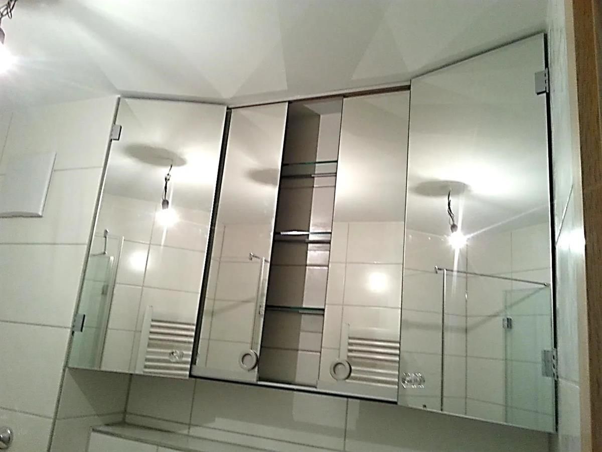 Ein Badezimmer mit drei Spiegeln und einem Handtuchhalter