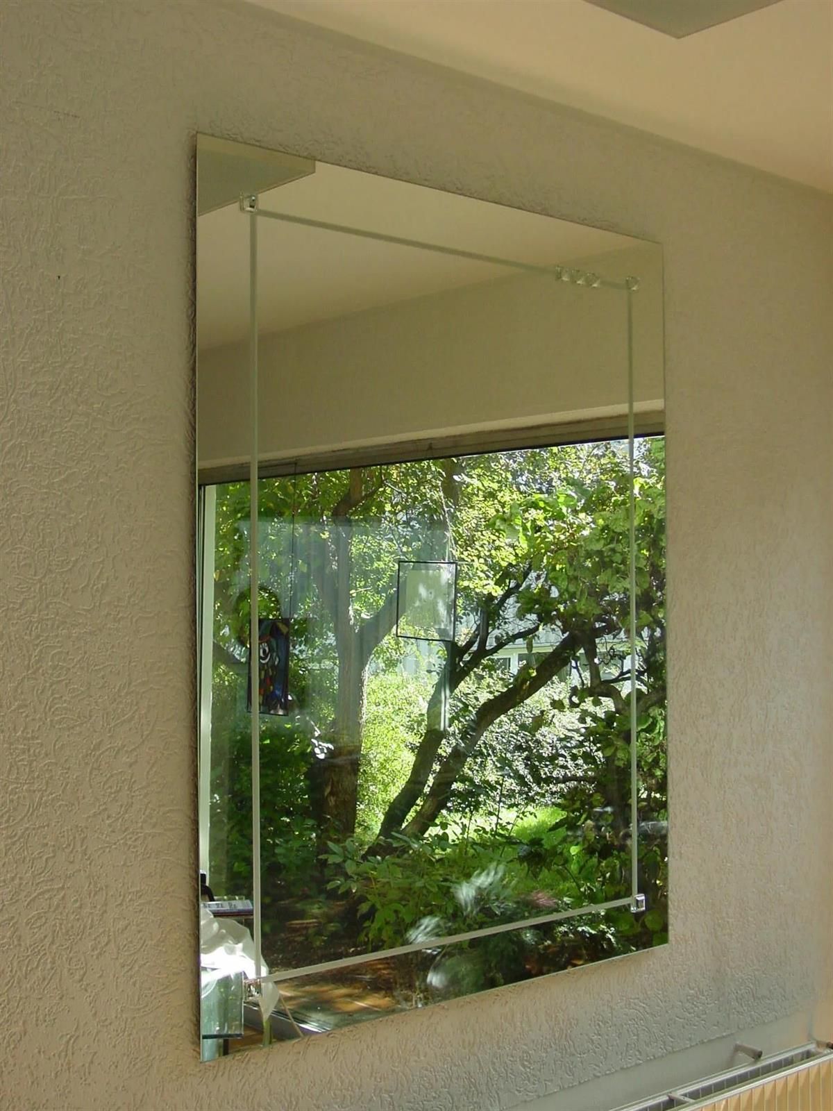 Ein großer Spiegel, der an einer Wand hängt und in dem sich Bäume spiegeln