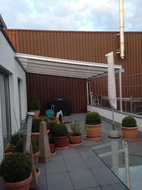 Ein Balkon mit Topfpflanzen und einer weißen Pergola