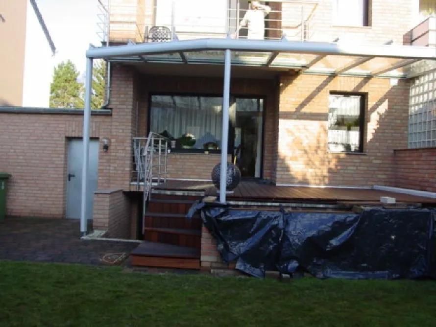 Ein Backsteinhaus mit einer Glasveranda und Treppen