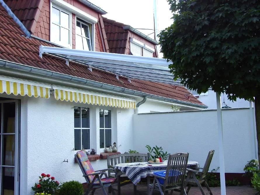 Ein weißes Haus mit einem Tisch und Stühlen unter einer Markise